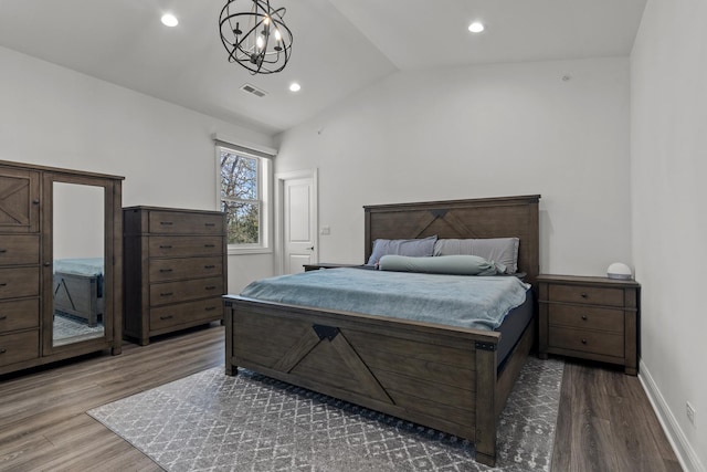 bedroom with visible vents, lofted ceiling, a notable chandelier, and wood finished floors