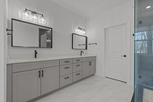 bathroom featuring double vanity, marble finish floor, a shower stall, and a sink