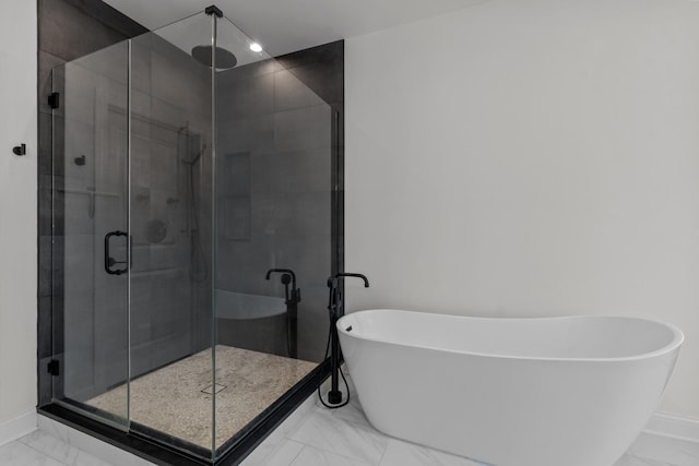 bathroom featuring baseboards, a freestanding bath, marble finish floor, and a shower stall