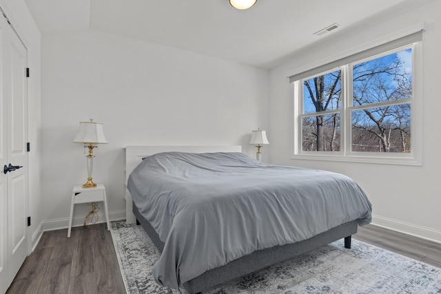 bedroom featuring lofted ceiling, wood finished floors, visible vents, and baseboards