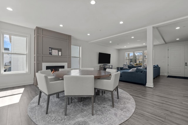 dining space featuring light wood-style flooring, recessed lighting, baseboards, and a large fireplace