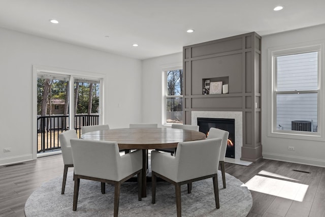 dining room with plenty of natural light, wood finished floors, visible vents, and a premium fireplace