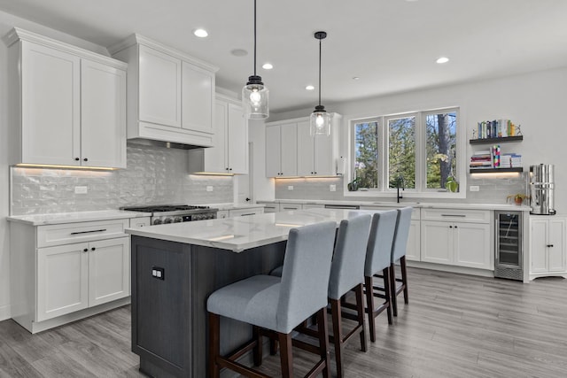 kitchen with beverage cooler, a kitchen island, white cabinetry, and a kitchen bar