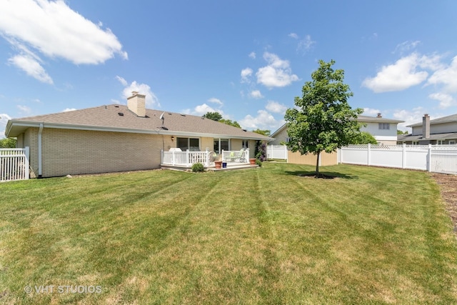 rear view of property featuring brick siding, a fenced backyard, a lawn, and a chimney