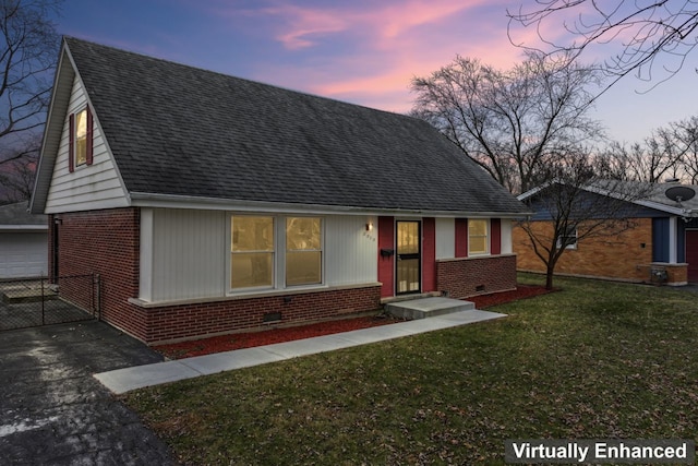 view of front facade featuring brick siding, a shingled roof, an outbuilding, and a yard