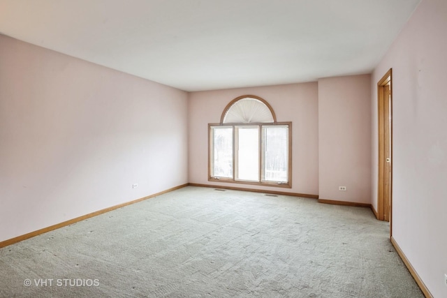 spare room with light colored carpet and baseboards