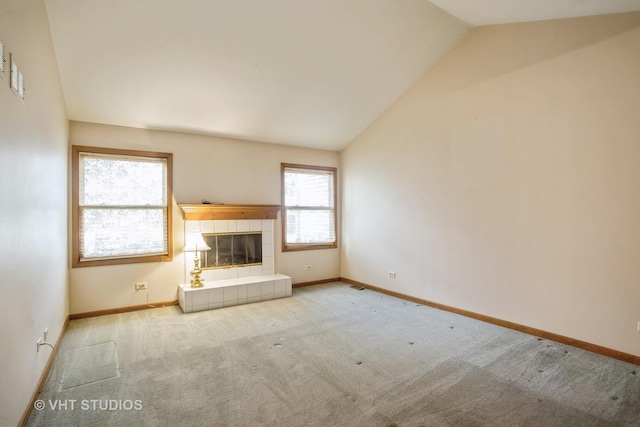 unfurnished living room with vaulted ceiling, carpet floors, baseboards, and a tiled fireplace