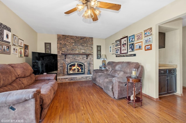 living room with baseboards, wood finished floors, ceiling fan, and a fireplace