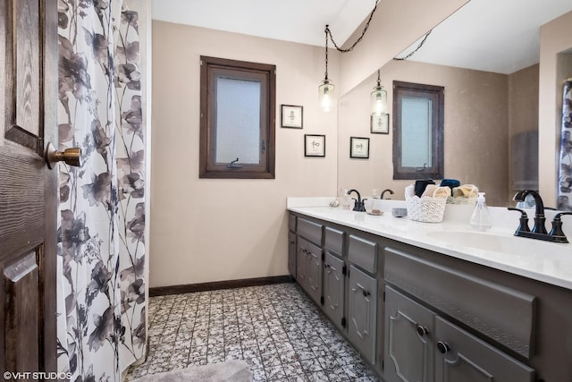 bathroom with double vanity, baseboards, and a sink