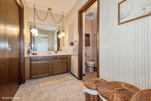 bathroom featuring visible vents, toilet, vanity, and wallpapered walls