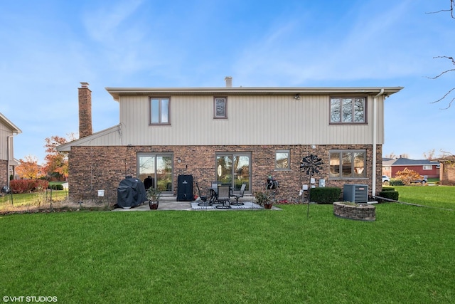 rear view of property with a yard, cooling unit, and a patio