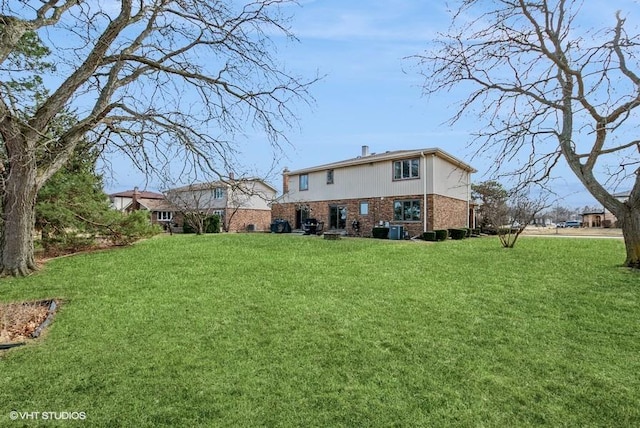 rear view of property featuring a yard, brick siding, and central AC