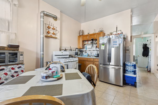 2020 W Superior St, Chicago, IL 60612 - kitchen featuring light tile patterned floors, a ceiling fan, brown cabinetry, white range with gas stovetop, and freestanding refrigerator