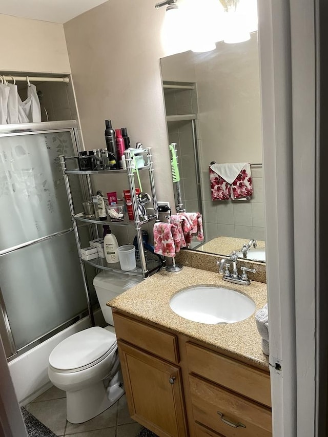 full bathroom with combined bath / shower with glass door, toilet, vanity, and tile patterned flooring