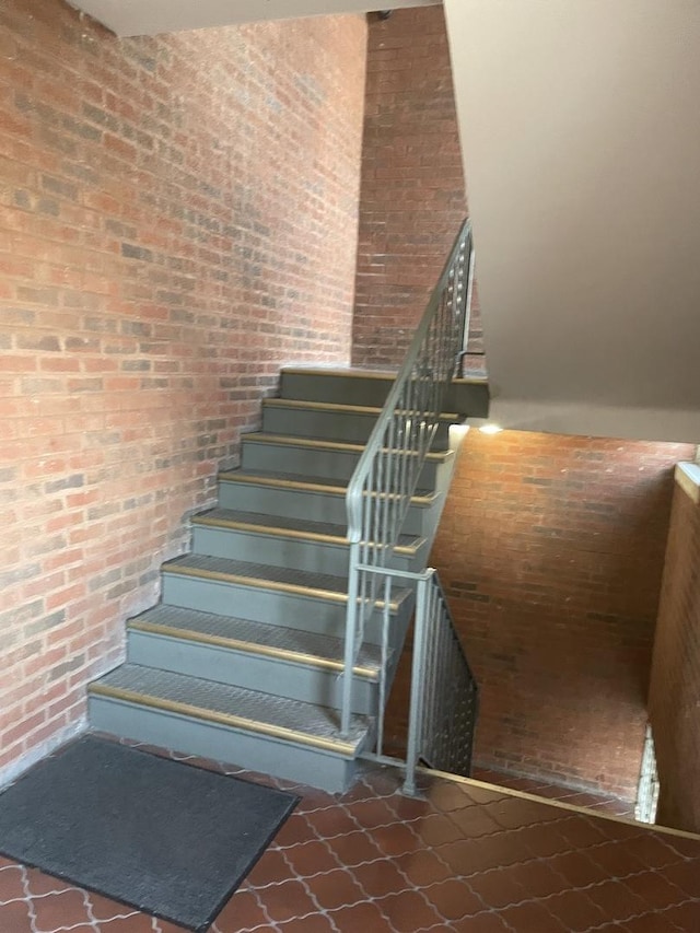 stairway with a towering ceiling and brick wall