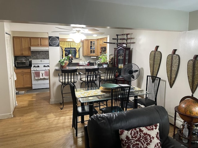 dining area featuring a toaster, light wood-style flooring, and a ceiling fan