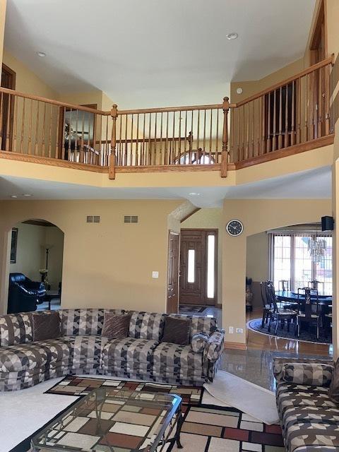 living room with a high ceiling, arched walkways, and visible vents