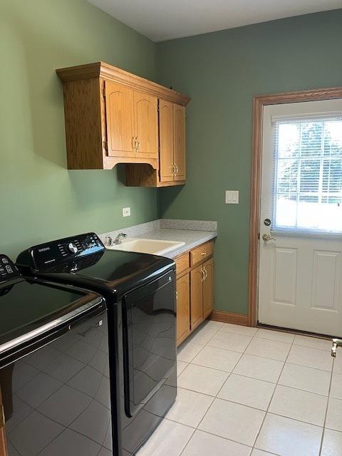 laundry room featuring light tile patterned floors, a sink, cabinet space, and separate washer and dryer