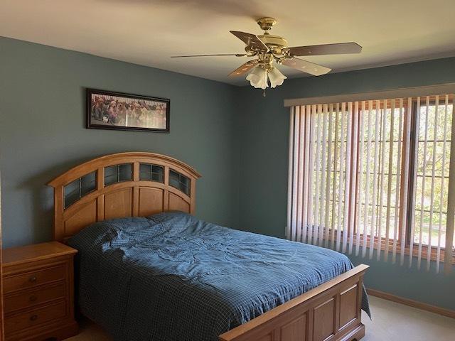 bedroom featuring a ceiling fan, light colored carpet, and baseboards