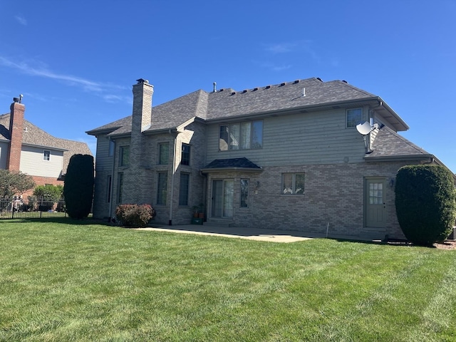 back of house with brick siding, fence, a chimney, a yard, and a patio