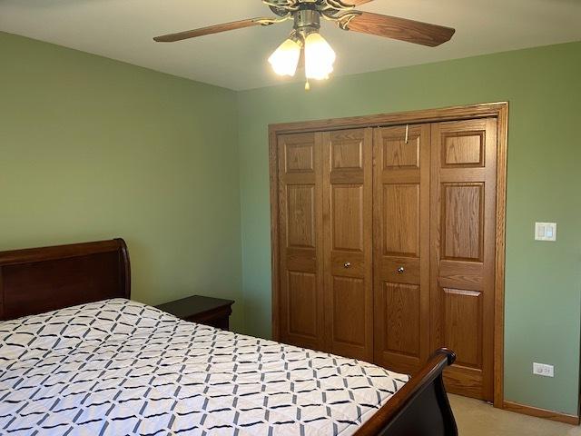 bedroom featuring a closet, light colored carpet, baseboards, and ceiling fan