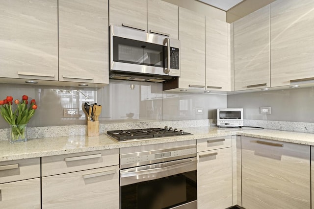 kitchen featuring modern cabinets, light stone counters, and appliances with stainless steel finishes