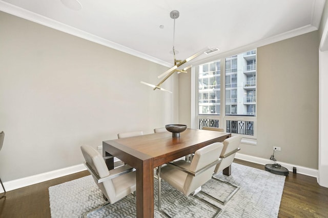 dining space featuring an inviting chandelier, crown molding, wood finished floors, and baseboards