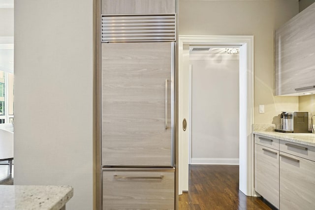 kitchen with dark wood finished floors, light stone counters, modern cabinets, and built in fridge