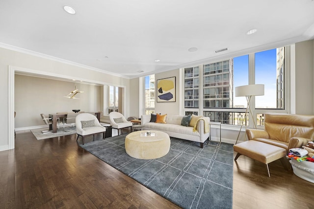 living area featuring visible vents, ornamental molding, baseboards, and wood finished floors