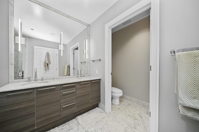 full bath featuring a sink, toilet, marble finish floor, and double vanity