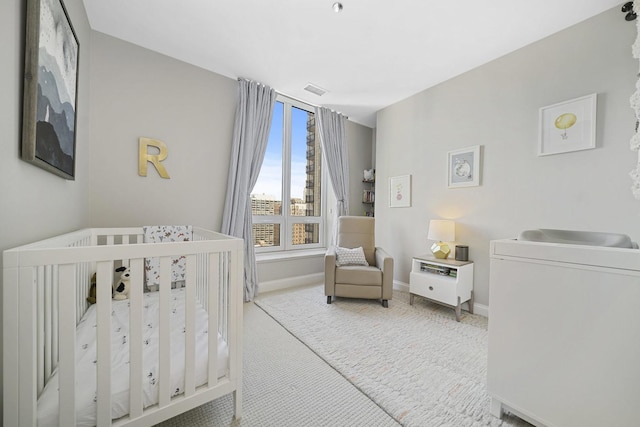 bedroom featuring carpet flooring, a nursery area, visible vents, and baseboards