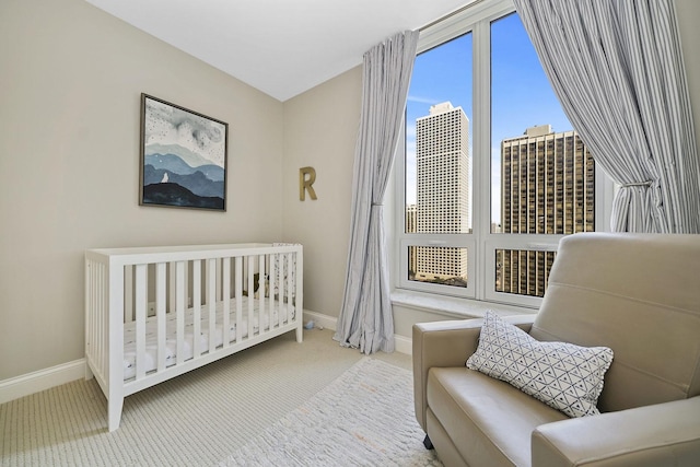 carpeted bedroom with baseboards and a nursery area