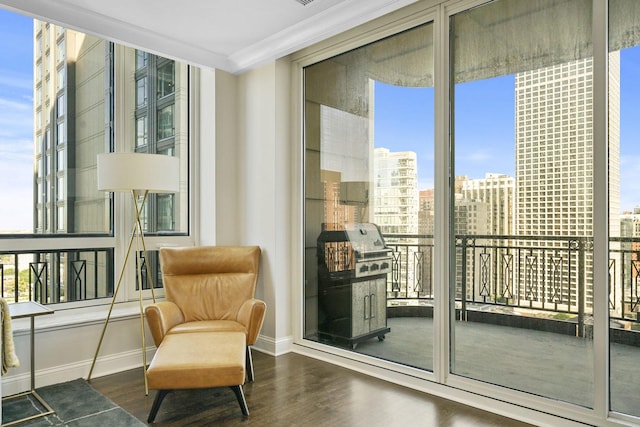 sitting room featuring expansive windows, wood finished floors, baseboards, and ornamental molding