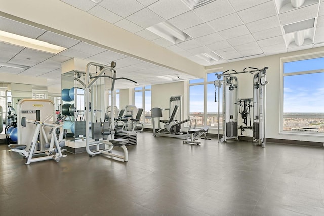 workout area featuring a paneled ceiling and baseboards