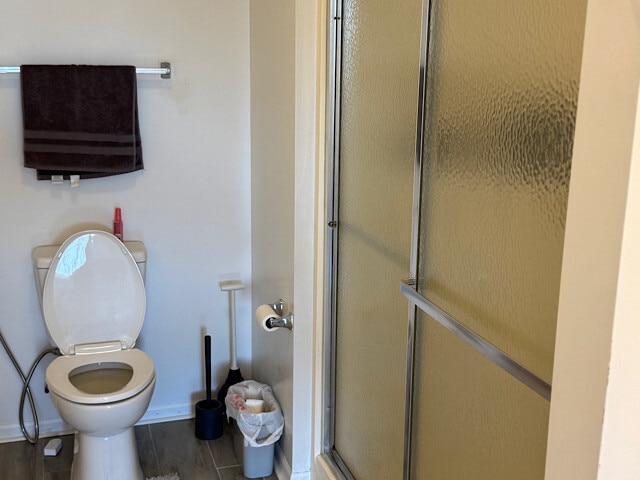 full bathroom with an enclosed shower, baseboards, and toilet