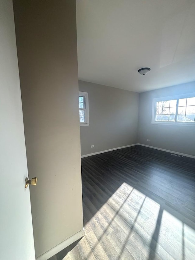 spare room featuring visible vents, baseboards, and wood finished floors