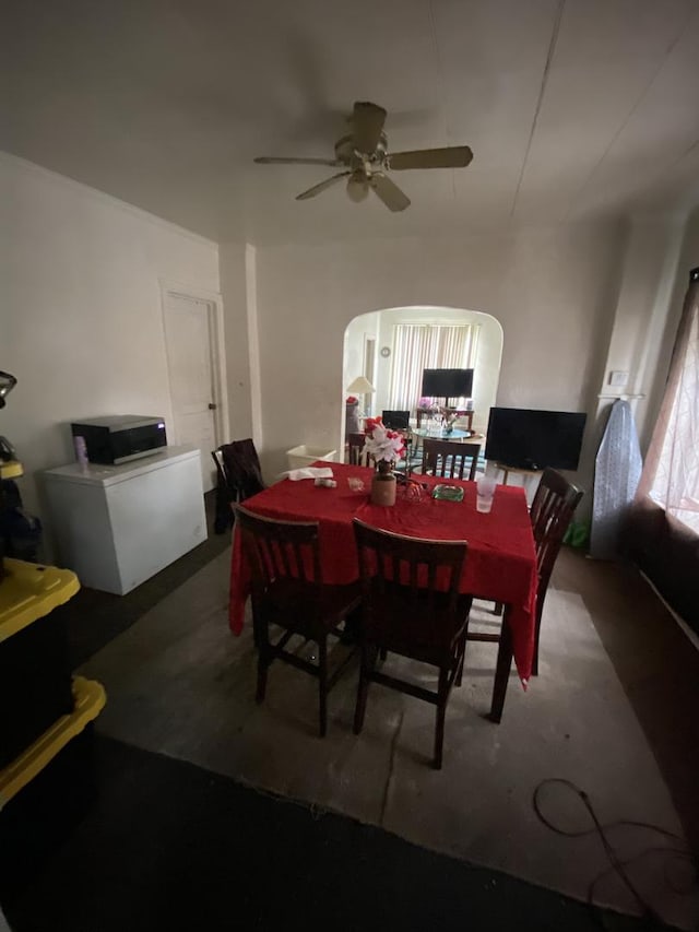 dining area with arched walkways and a ceiling fan