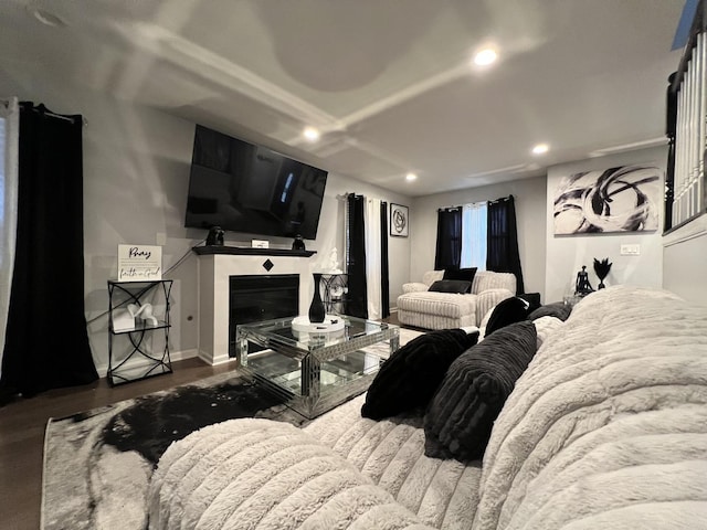 bedroom with recessed lighting, baseboards, a glass covered fireplace, and wood finished floors