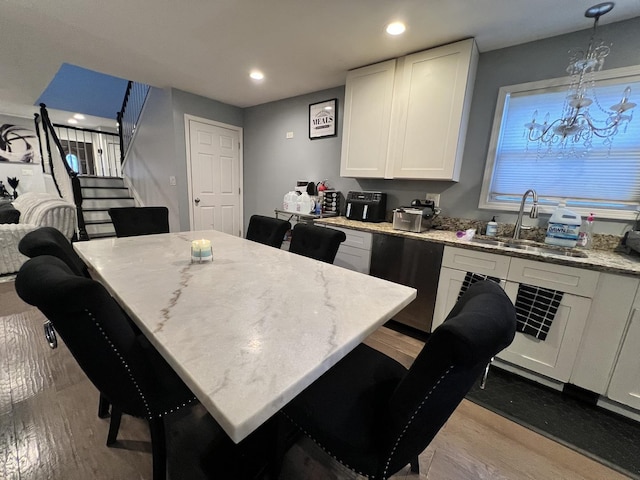 kitchen featuring a sink, light stone countertops, wood finished floors, and white cabinets