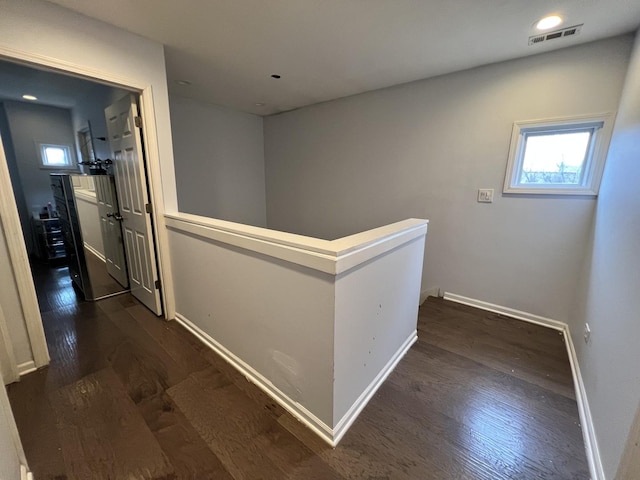 hall featuring visible vents, an upstairs landing, baseboards, and dark wood-style floors