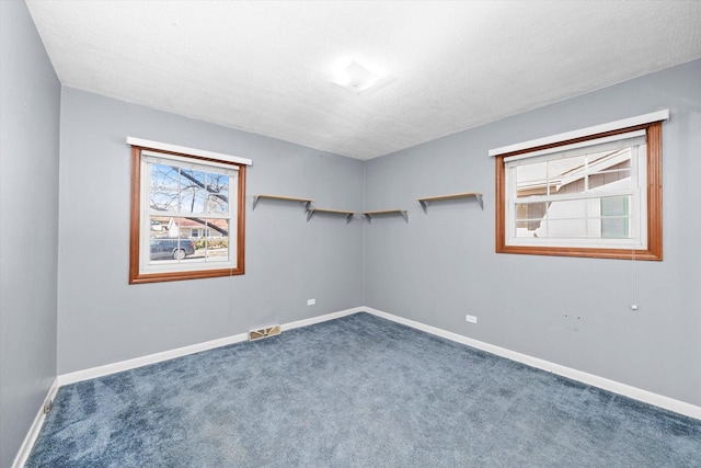 carpeted empty room with visible vents, baseboards, and a textured ceiling