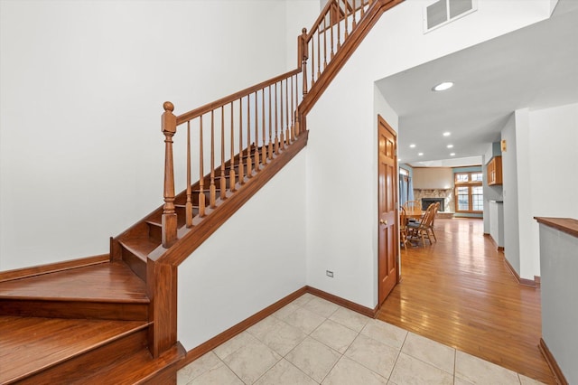 stairs with wood finished floors, baseboards, visible vents, recessed lighting, and a towering ceiling