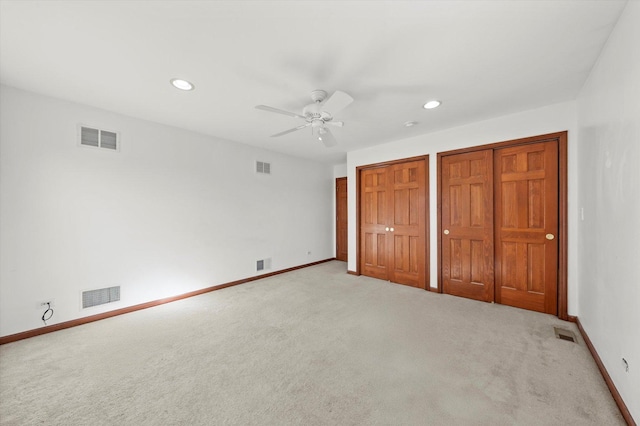 unfurnished bedroom with visible vents, carpet flooring, and multiple closets