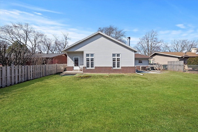 back of house with a yard, brick siding, a fenced backyard, and a patio area