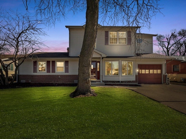 traditional-style house with concrete driveway, a yard, brick siding, and a garage