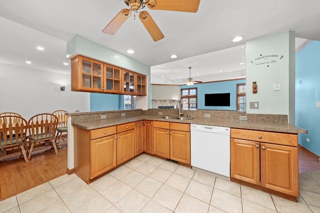 kitchen with light tile patterned flooring, a sink, ceiling fan, glass insert cabinets, and dishwasher