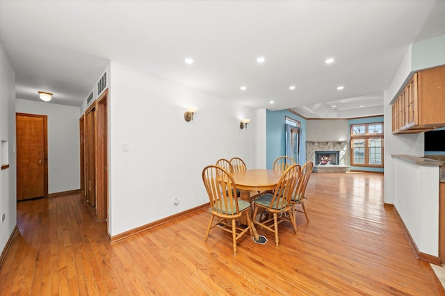 dining room with recessed lighting, a fireplace, baseboards, and light wood finished floors