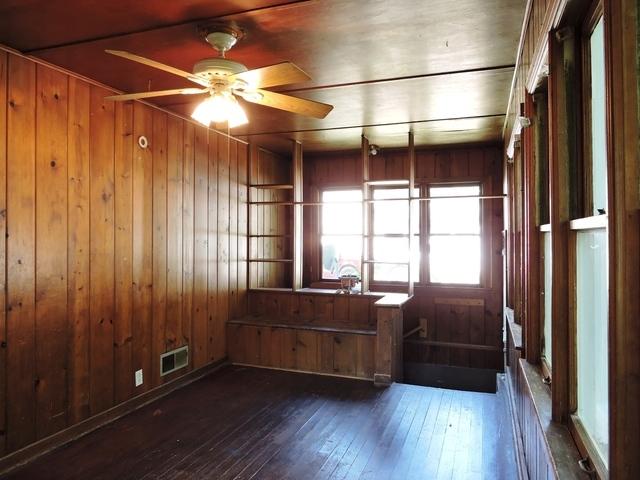 833 Pleasant St, Dekalb, IL 60115 - unfurnished room featuring hardwood / wood-style flooring, wooden walls, and a ceiling fan