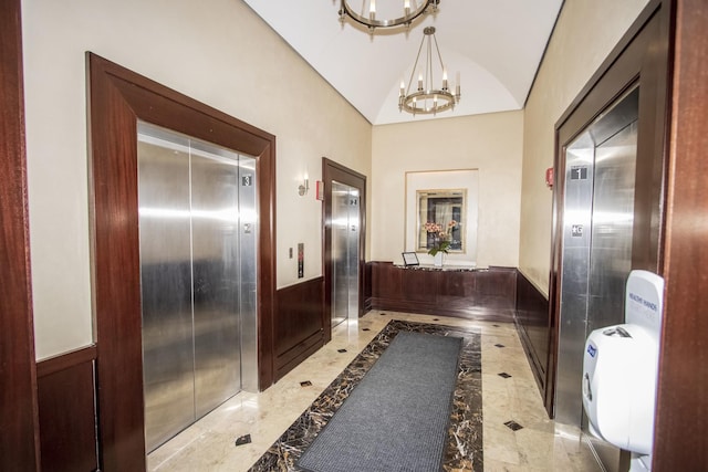 hall with elevator, marble finish floor, and an inviting chandelier