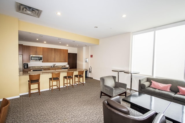 carpeted living area with recessed lighting, baseboards, and a sink